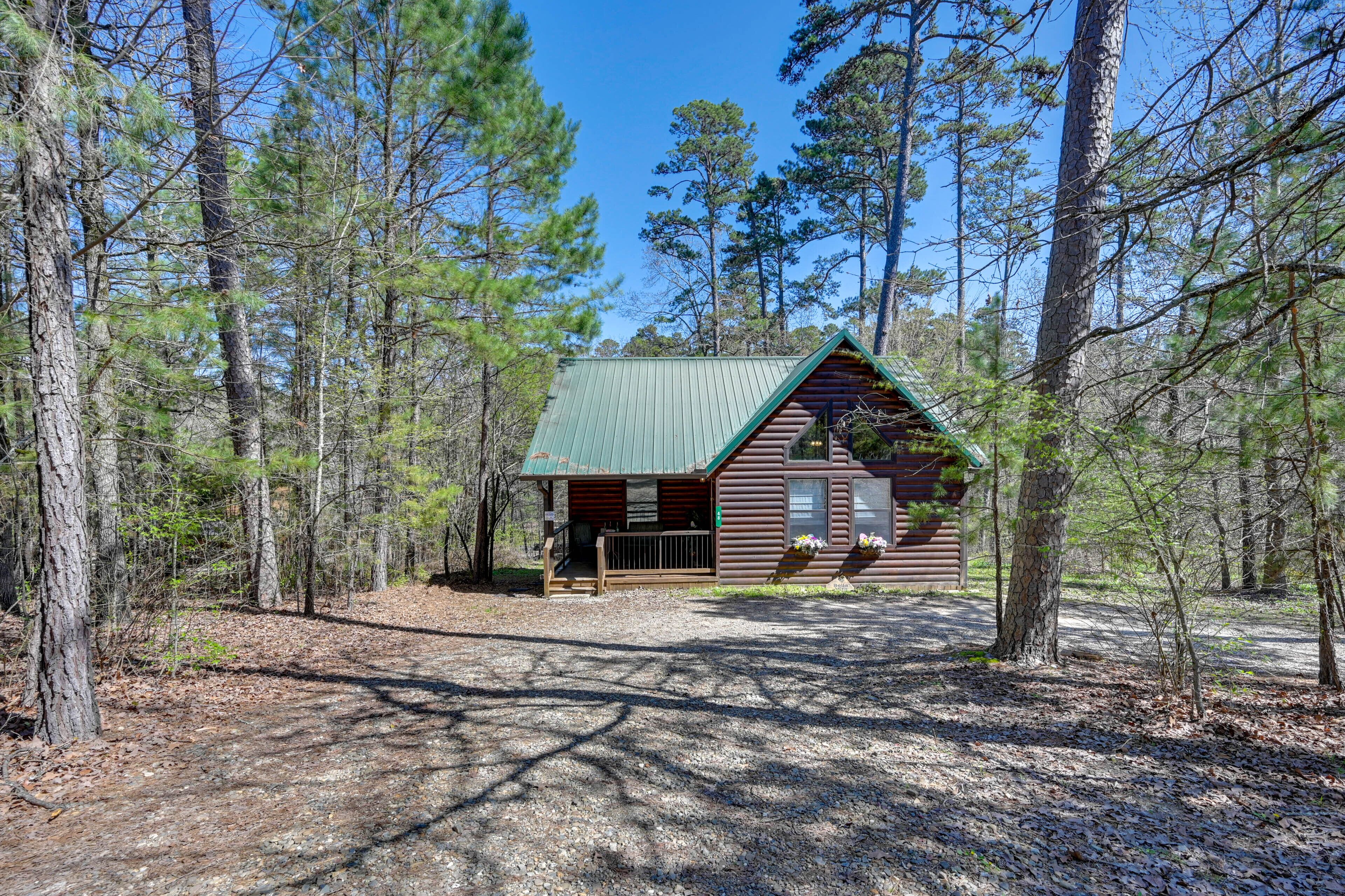 A cabin with a green roof, surrounded by tall pine trees.
