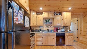 A kitchen with wooden cabinets, a refrigerator, and a sink. - Broken Bow Cabin w/ Hot Tub & Fire Pit, Near Lake! (Broken Bow)