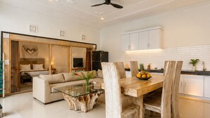 A modern living room with a glass coffee table, wooden dining table, and chairs. - Prime location just walking distance to the Boutique shop, Restaurant , Bar (Seminyak)