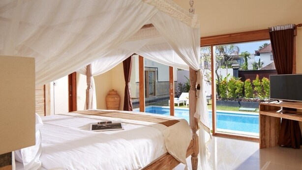 A bedroom with a bed, a bedside table, a TV, and a view of a swimming pool. - Prime location just walking distance to the Boutique shop, Restaurant , Bar (Seminyak)