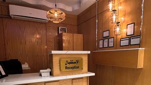 Un área de recepción con un mostrador de madera, un letrero que dice 'Reception' y una lámpara fijada a la pared.
