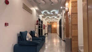 Un vestíbulo de hotel con una recepción, un área de espera con sofás azules y una pared de madera.