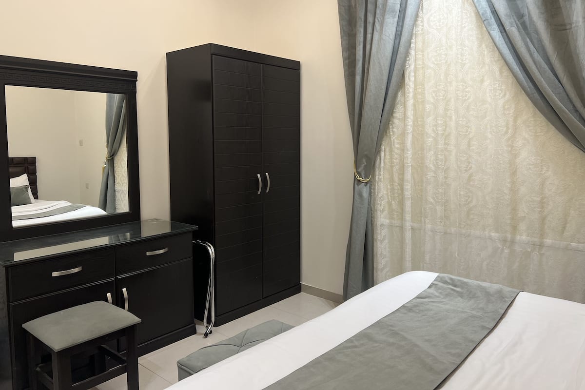A bedroom with a bed, a dresser, a mirror, and a wardrobe.