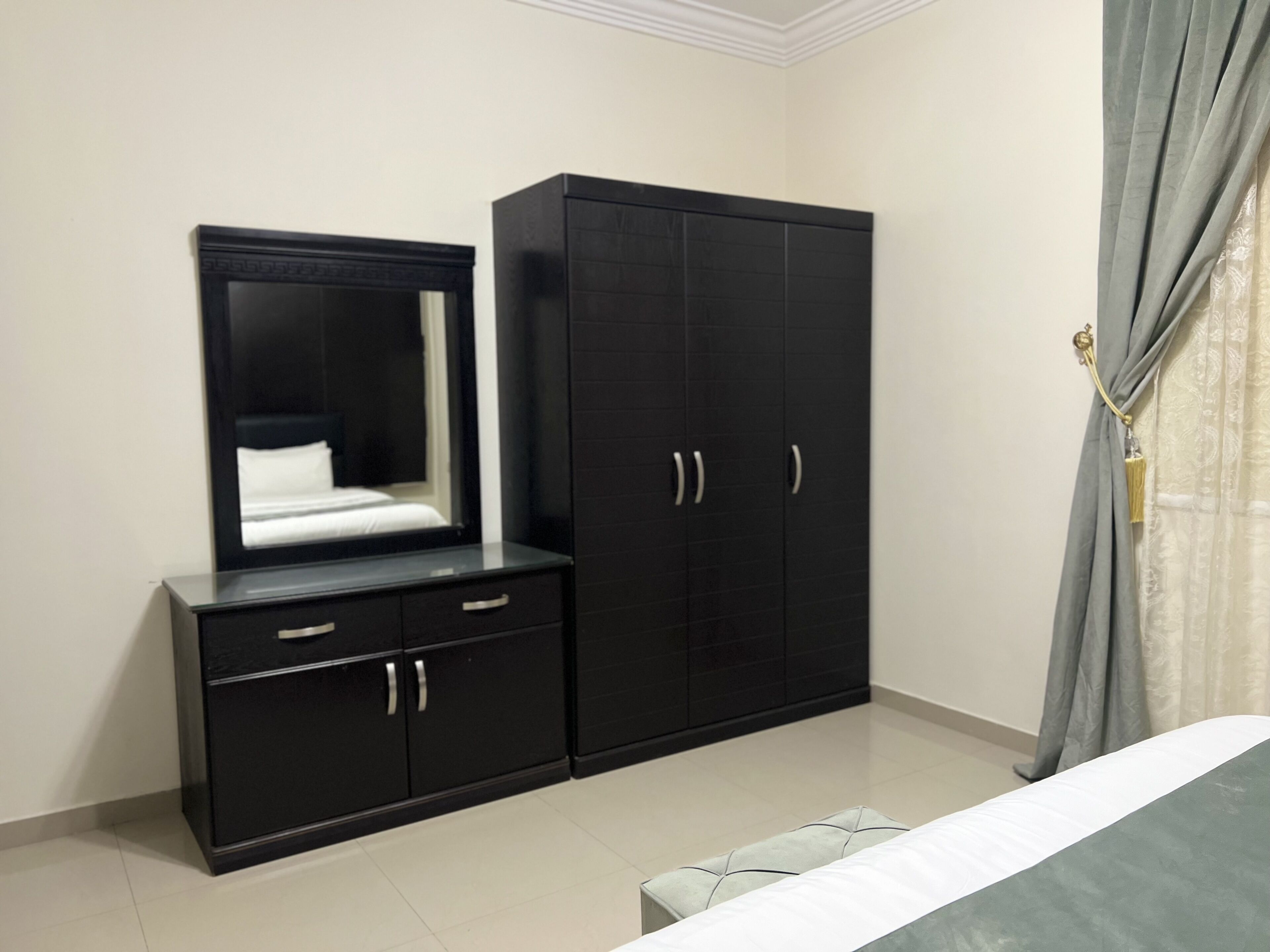A bedroom with a bed, a dresser, a mirror, and a wardrobe.