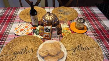 A table set with various food items, including a bottle of wine, a pumpkin, and a plate of cookies, on a plaid tablecloth.