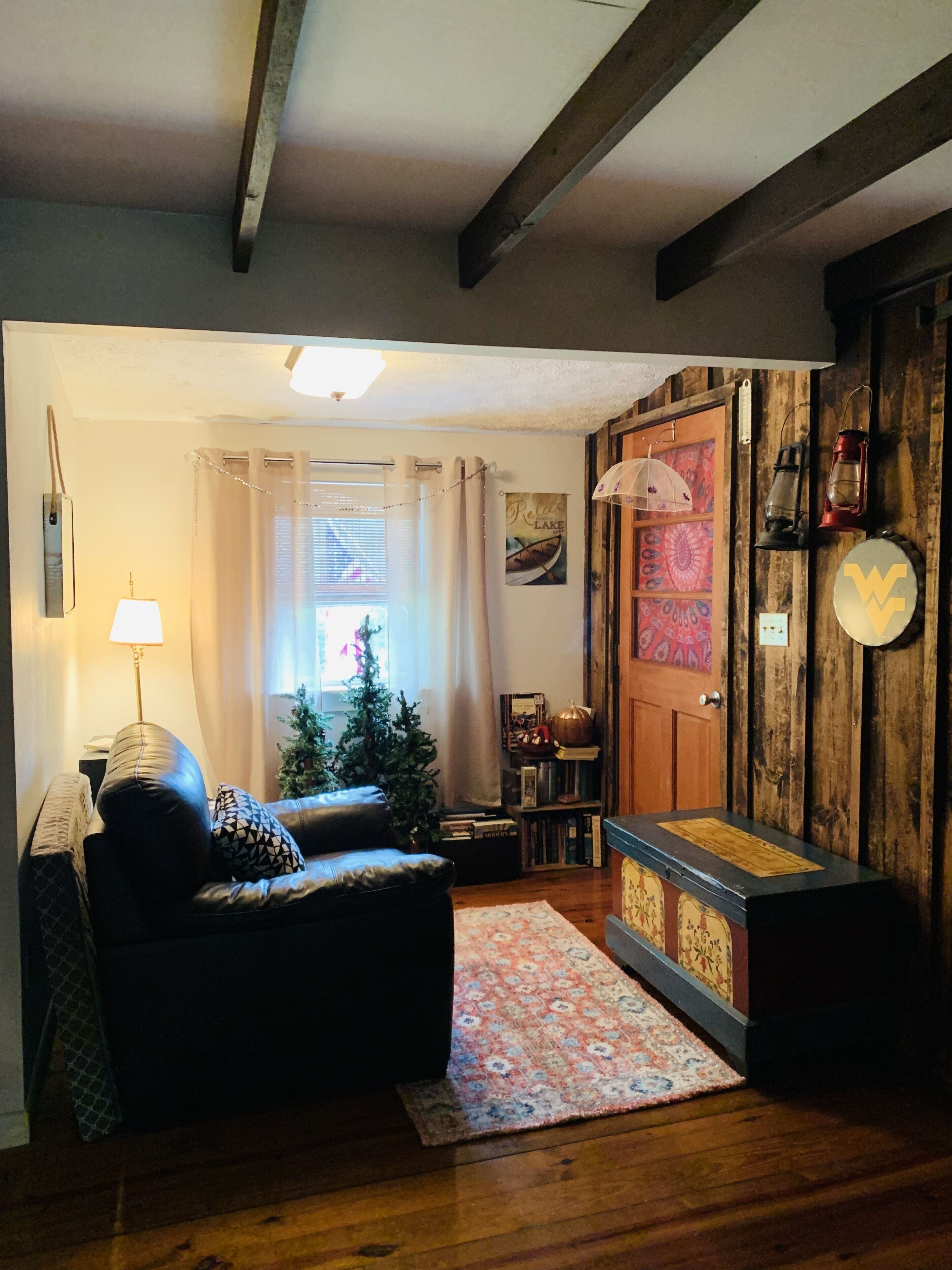 Ein gemütliches Wohnzimmer mit Ledersofa, einem kleinen Weihnachtsbaum und einer Holztür mit dekorativem Wappen.
