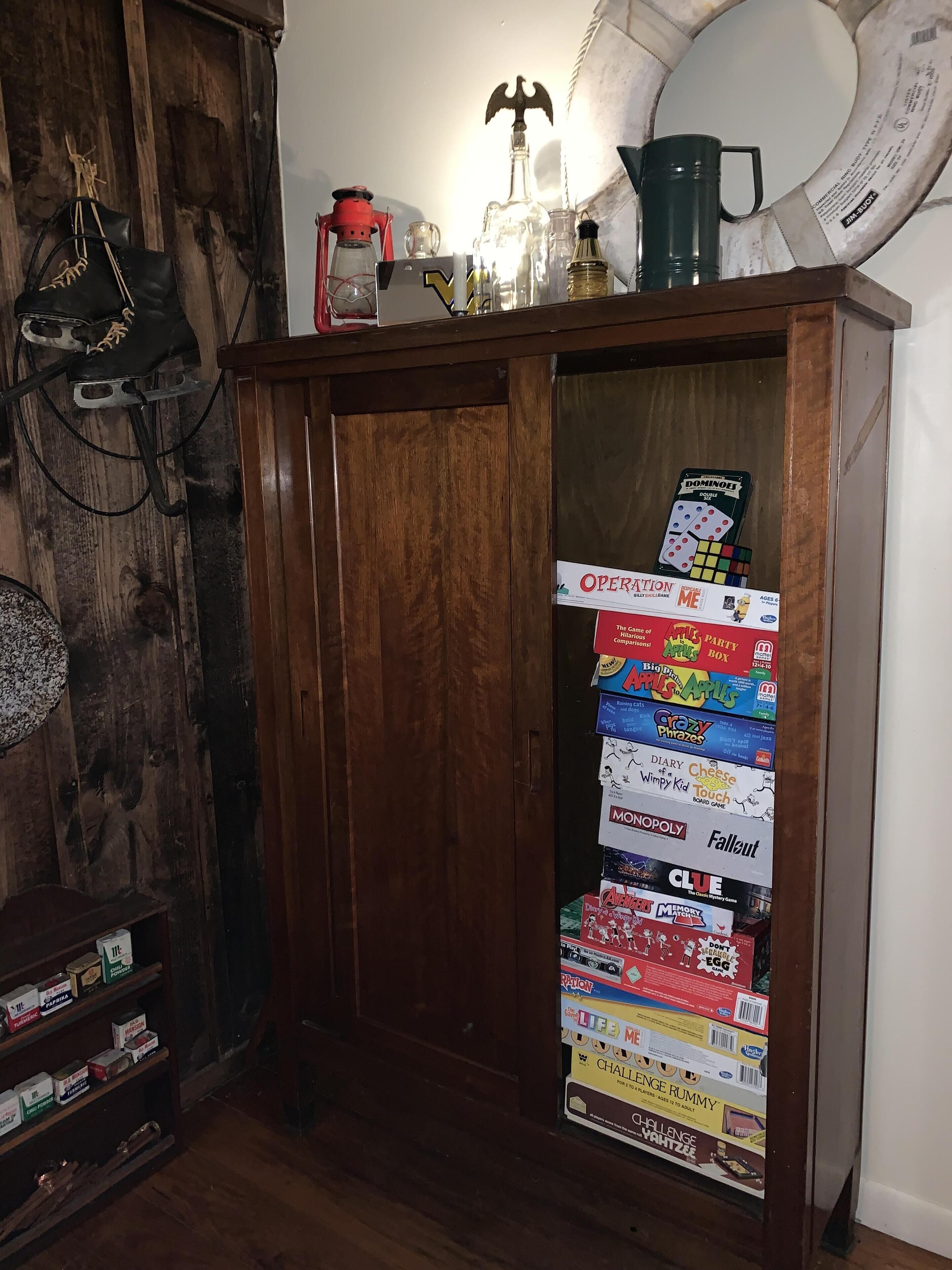 Un meuble en bois doté d’une porte en verre, derrière laquelle on peut voir différents jeux de société.