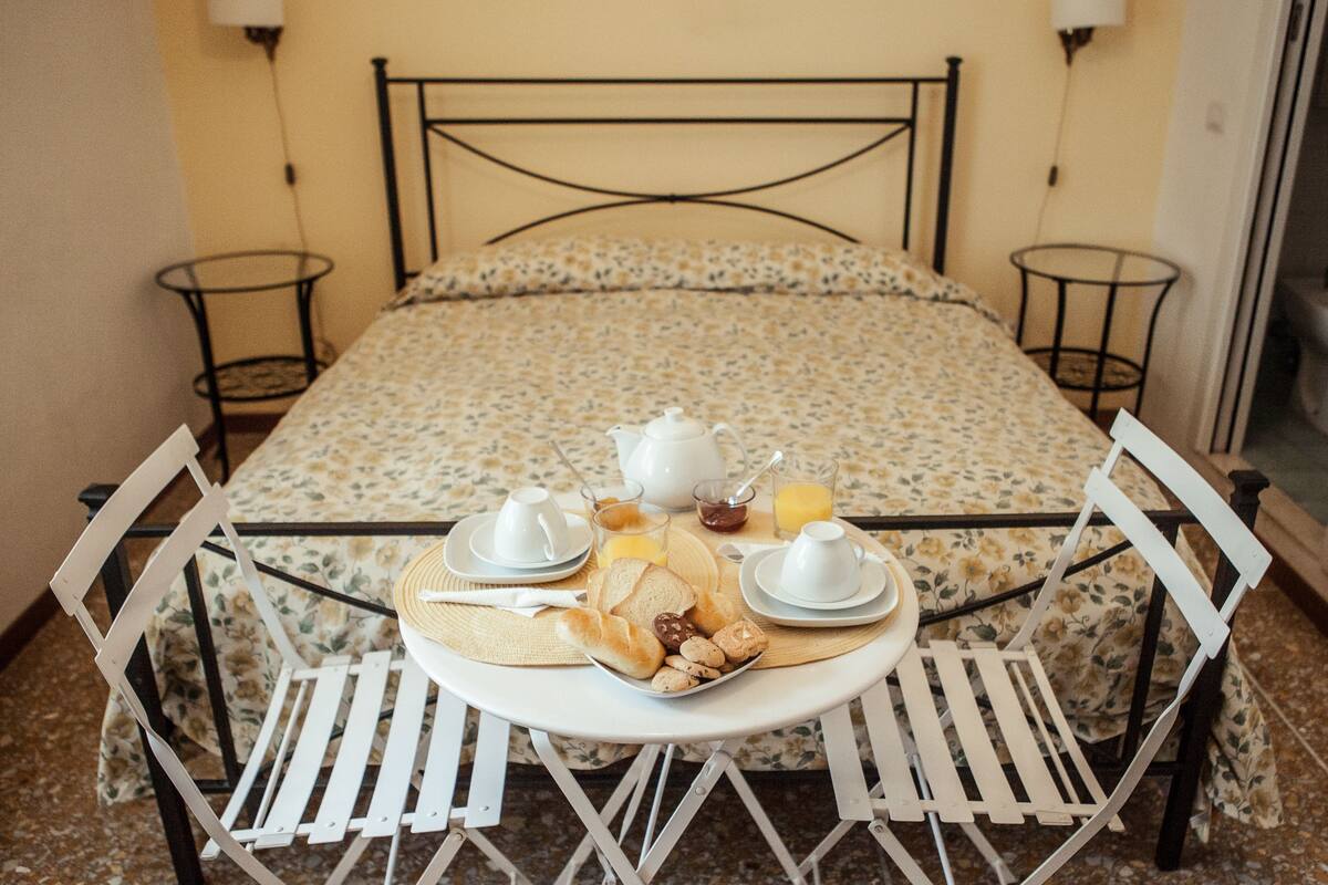 A neatly arranged breakfast table with a floral bedspread, a metal-framed bed, and two bedside tables.