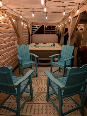 A cozy room with a hot tub, wooden walls, and blue chairs.