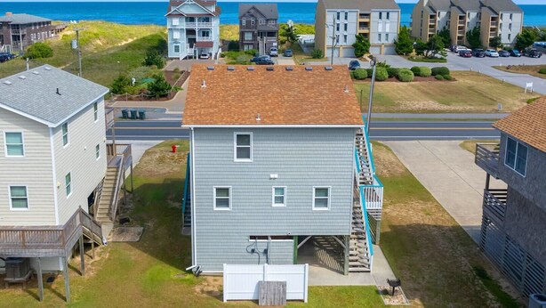 Un quartier résidentiel avec une maison à deux étages, dotée d’un garage, d’une petite terrasse et d’un escalier menant à un balcon.