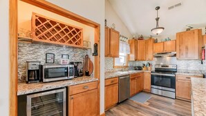 Una cucina con mobili in legno, forno integrato, lavastoviglie e microonde.