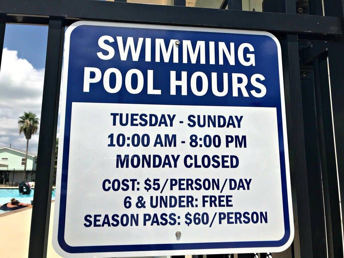 A sign detailing swimming pool hours, costs, and age-related pricing.