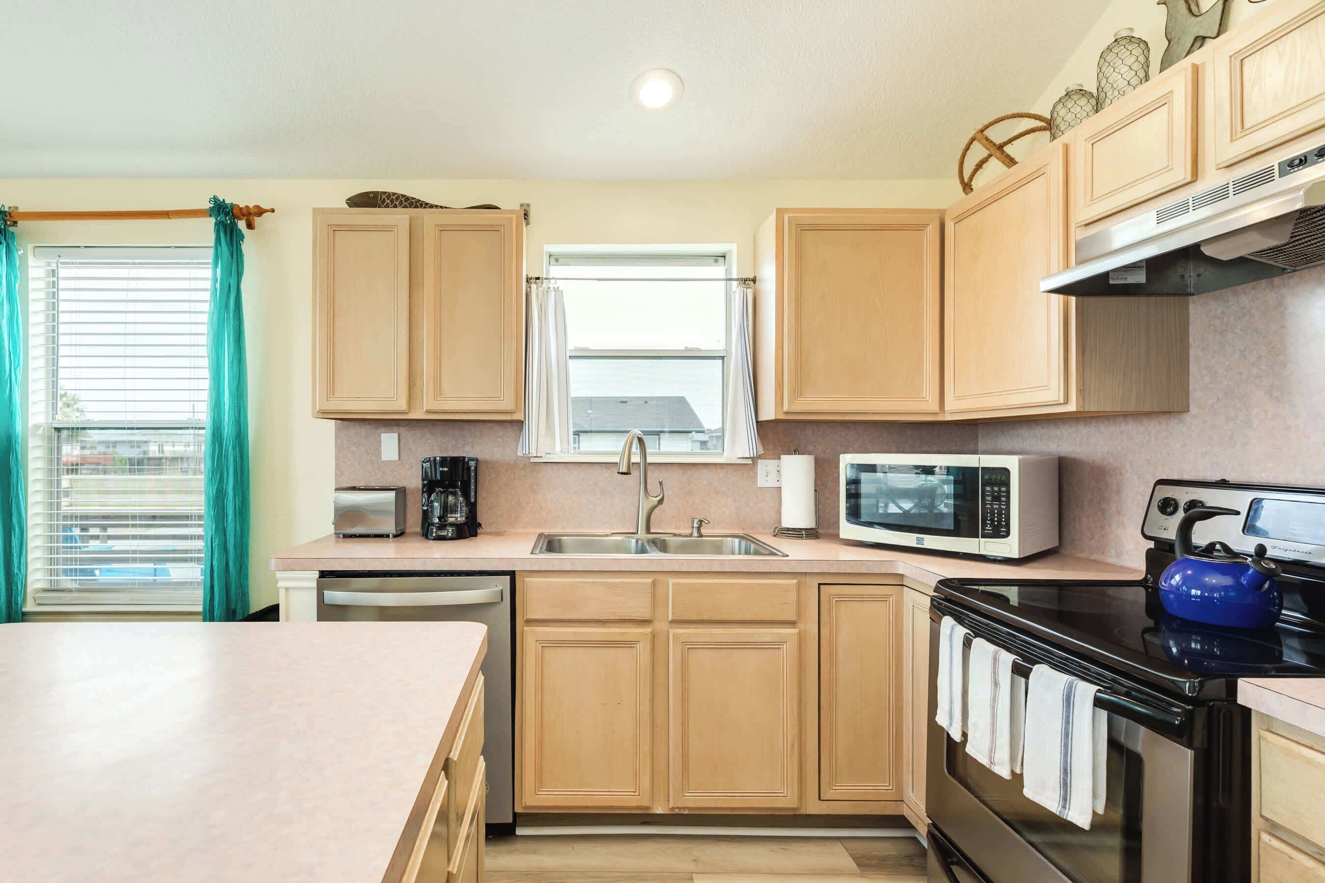 A kitchen with wooden cabinets, a microwave, a stove, and a kettle.