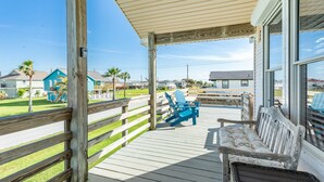 A wooden deck with a covered area, blue Adirondack chairs, and a bench. - Jamaica Beach Gem - Huge Deck, Fenced, Pups Welcome! (Jamaica Beach)