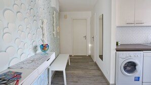 Un cuarto de lavado con lavadora, un banco y una mesa con un frutero.