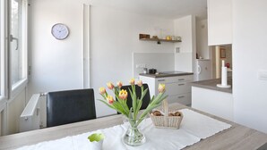 Una cocina moderna con armarios blancos, una encimera y una estantería colgante con frascos.