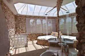 A bathroom with a skylight, stone walls, and two sinks. - Private Oceanfront Villa for Epic Group Getaways (Islote Arecibo)
