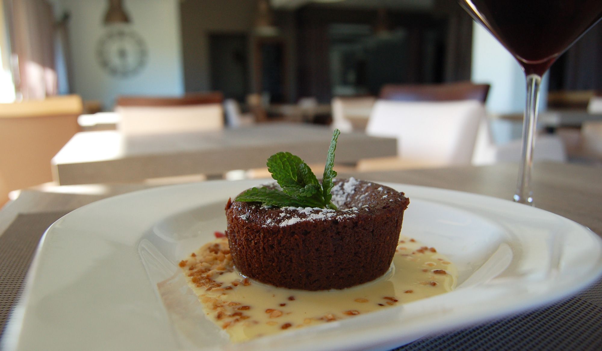 A dessert on a plate with a glass of red wine in the background.