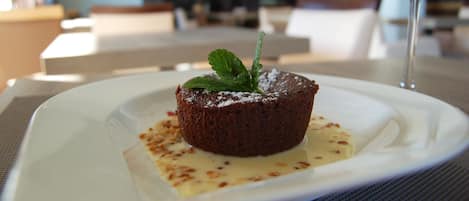 Un postre en un plato con una copa de vino tinto al fondo.