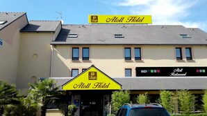 A hotel with a yellow sign reading "Atoll Hotel" and a smaller sign below it.