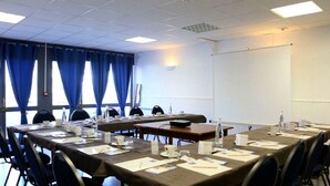 A conference room with long tables, chairs, nameplates, and a projector screen.