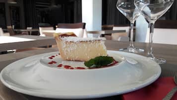 Un dessert servi dans une assiette blanche, décoré d’une feuille de menthe, accompagné d’un verre de vin blanc posé sur une table.