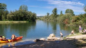Ein ruhiger Fluss mit Leuten, die Kajak fahren und am Ufer stehen.