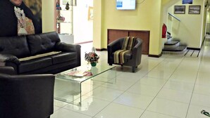A lobby with a black leather sofa, a glass coffee table, a grey armchair, a television mounted on the wall, and a staircase leading to an upper floor. - Hotel Newen (Temuco)
