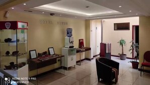 A hotel reception area with a reception desk, a water dispenser, a coffee machine, and a display of decorative items. - Hotel Newen (Temuco)