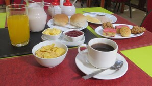 A breakfast setting with a table set for two, including plates with food, a glass of orange juice, a jug of milk, and a cup of coffee. - Hotel Newen (Temuco)