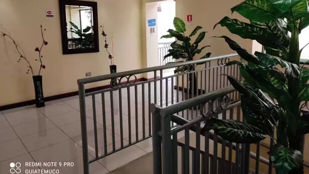 A hotel lobby with a tiled floor, a metal railing, and potted plants. - Hotel Newen (Temuco)