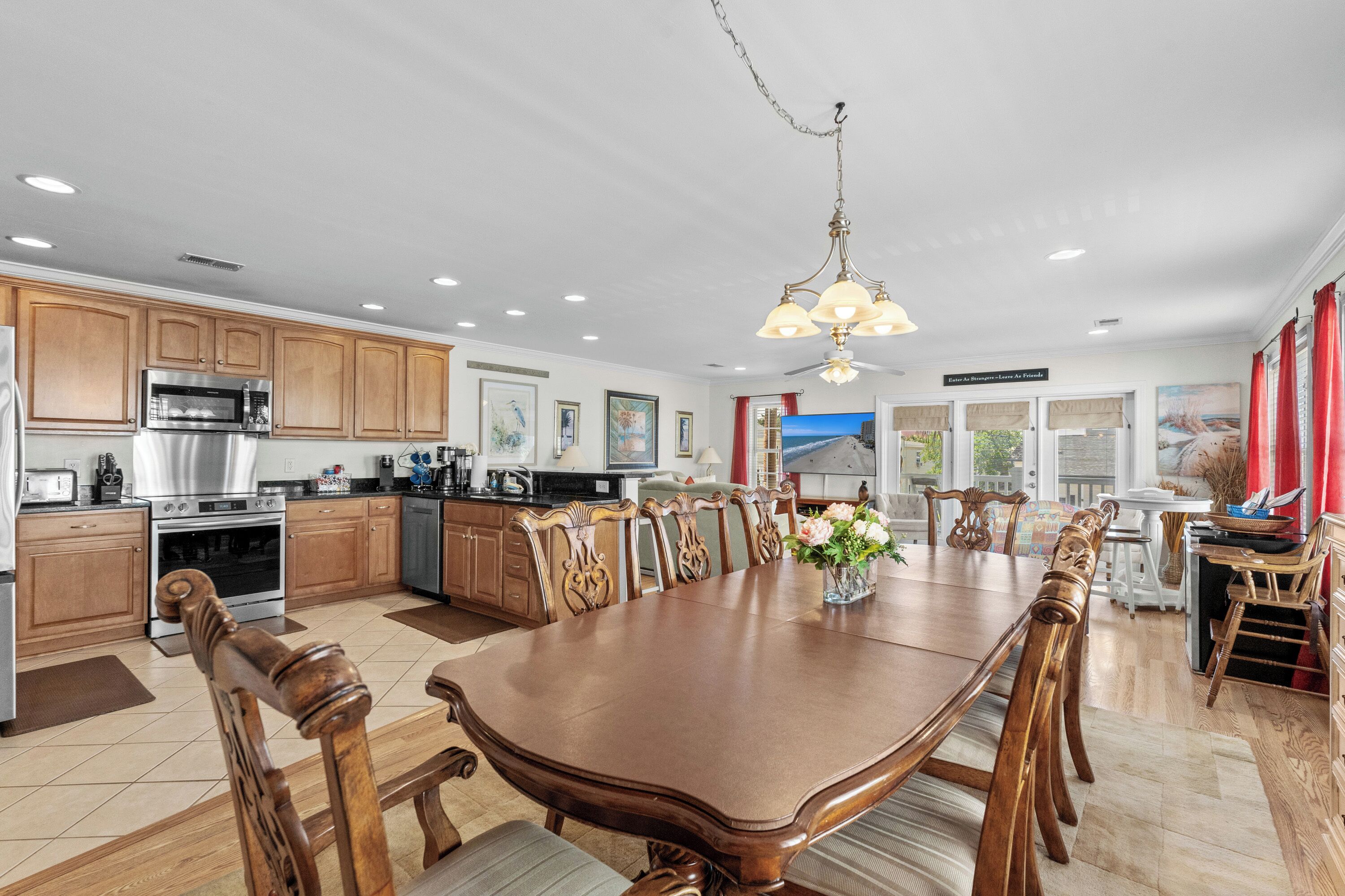 A spacious kitchen with wooden cabinets, a large dining table, and a chandelier.