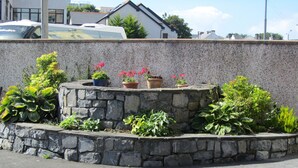 A stone planter with various potted plants and flowers. - Comfortable, Modern, Luxury, Secure, Beachfront, Seafront, City Centre (Galway)