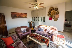 A living room with a ceiling fan, a sofa set, a coffee table, and a wall with decorative plates.