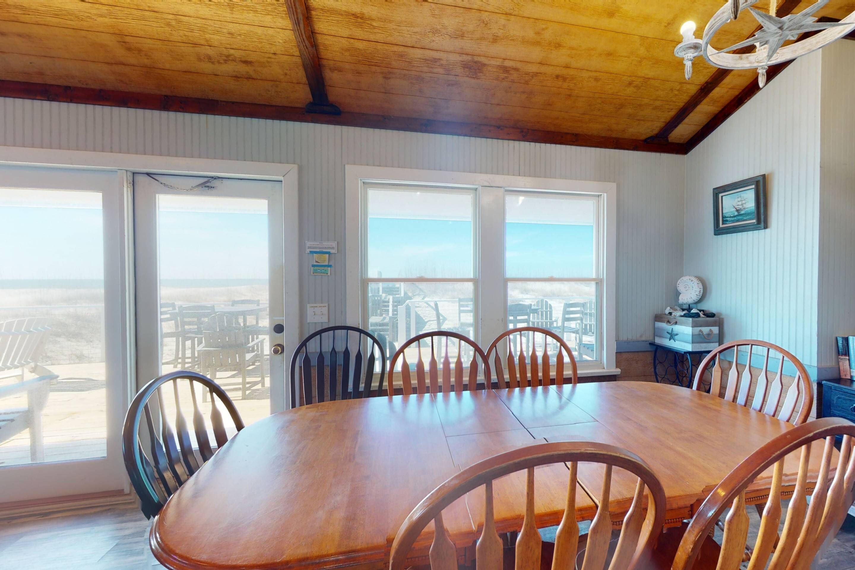 A dining room with a wooden table and chairs, large windows, and a view of the city.