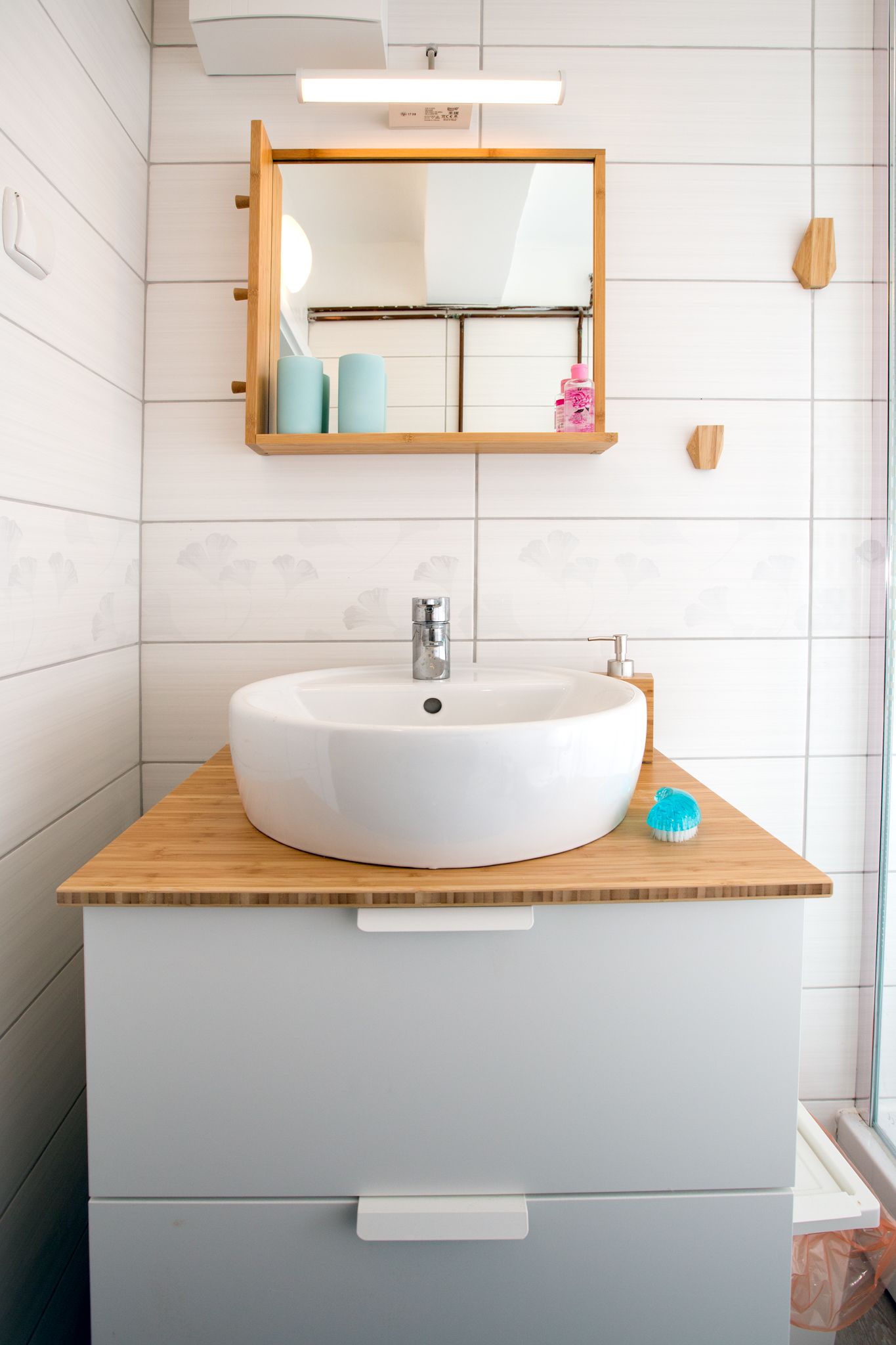 Un baño con lavamanos blanco, encimera de madera y un espejo encima.
