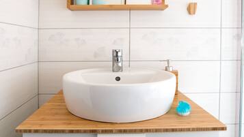 Un baño con lavamanos blanco, encimera de madera y un espejo encima.