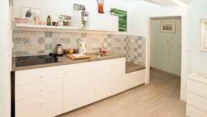 A kitchen with a tiled backsplash, white cabinetry, and a wooden countertop. - Big Yard (Ljubljana)