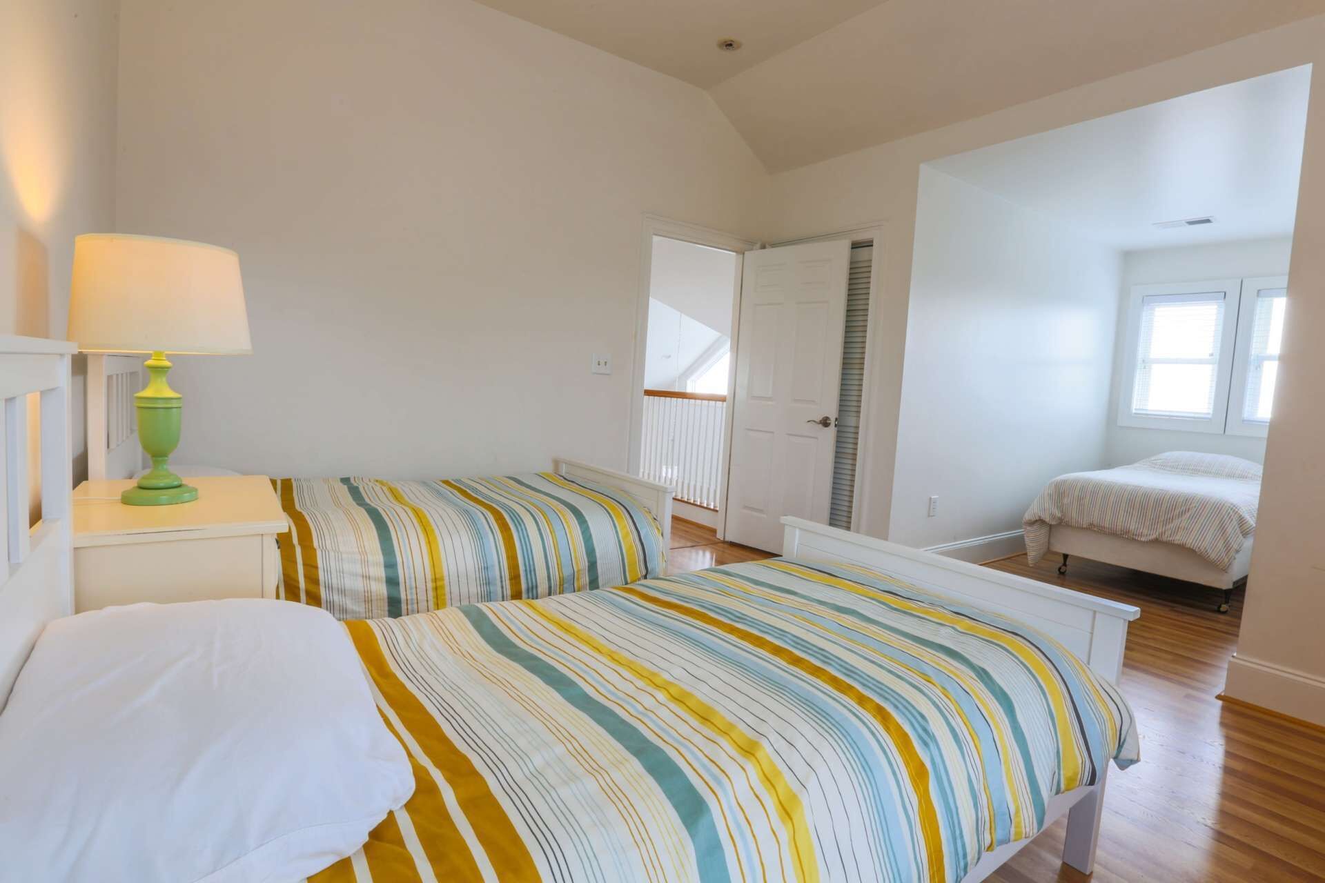 Un dormitorio con cama, mesita de noche, lámpara y ventana.