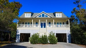 A two-story house with a front porch, garage doors, and a symmetrical facade.