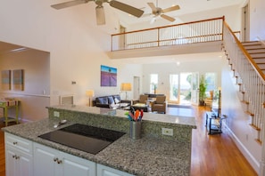 A spacious living area with a kitchen island, a dining area, and a staircase leading to an upper level. - Steps to Beach. Relax in Dog Friendly Ocean View Home, 2 Master Suites & Porch (Folly Beach)