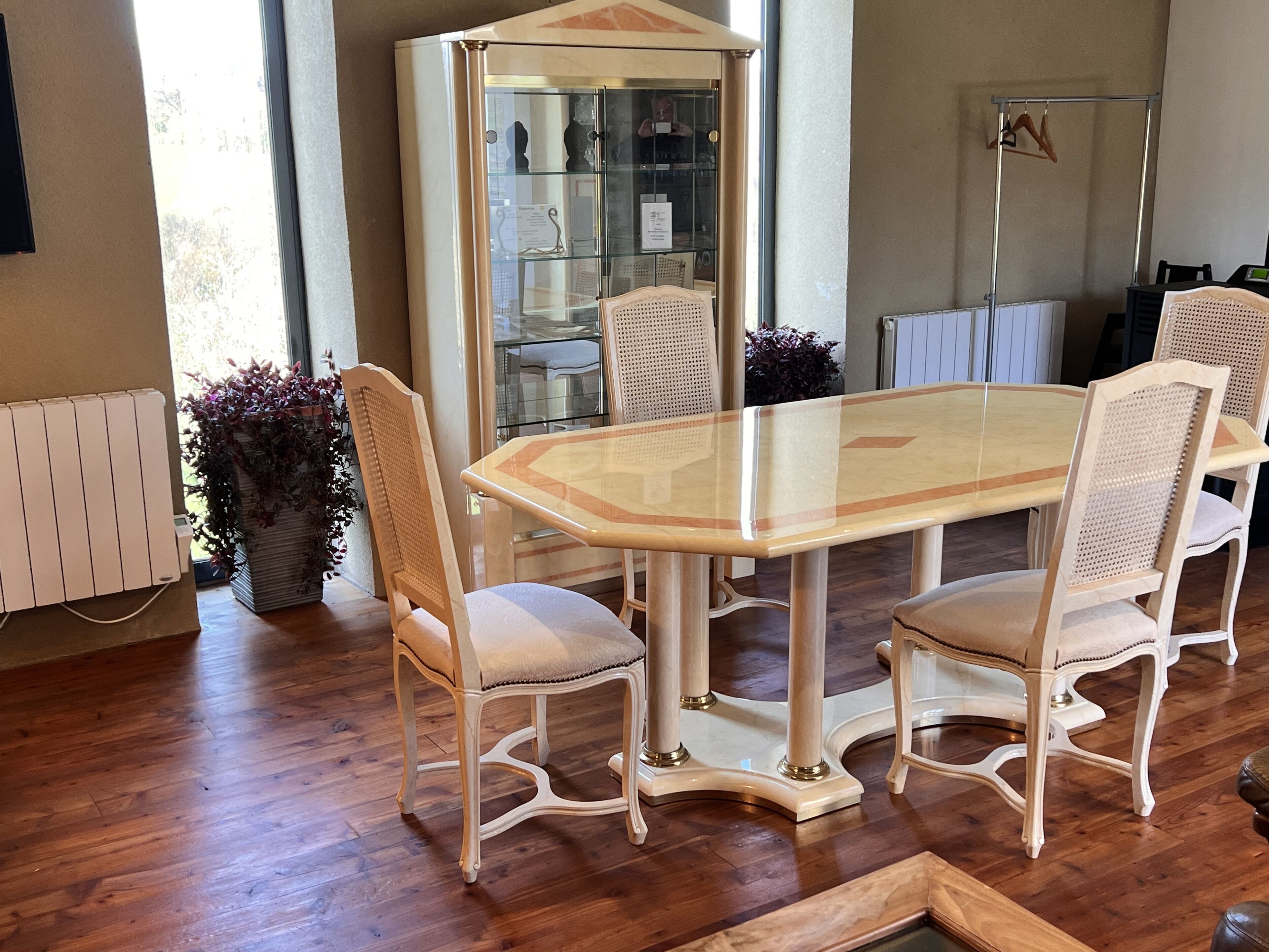 Un espace repas avec une table à plateau de verre, entourée de quatre chaises rembourrées à ossature en bois.