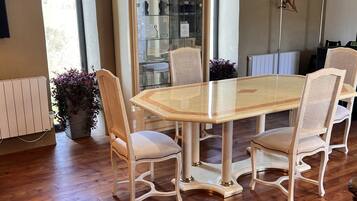 Un espace repas avec une table à plateau de verre, entourée de quatre chaises rembourrées à ossature en bois.