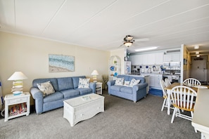 A compact living space with a sofa, a coffee table, and a dining area with chairs. - XPLORIE ACTIVITIES & LINENS INCLUDED*! OUTDOOR POOL (IN SEASON), TENNIS & MORE!!! (Ocean City)