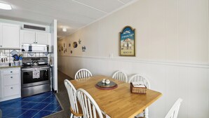 Una cocina con armarios blancos, una estufa de acero inoxidable y un suelo de azulejos azules.