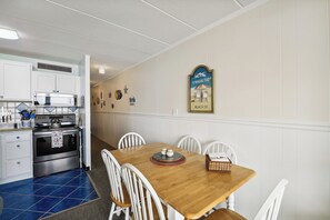 Una cocina con armarios blancos, una estufa de acero inoxidable y un suelo de azulejos azules.