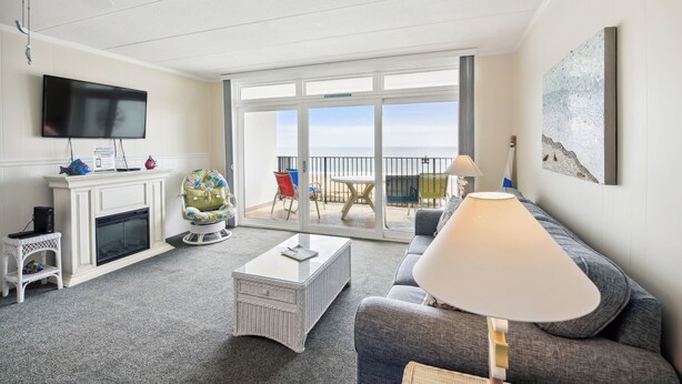 Una sala de estar con chimenea, televisor, sofá, mesa de centro y balcón con vistas.