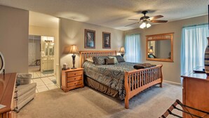 A bedroom with a wooden bed, bedside lamps, a ceiling fan, and a large mirror.