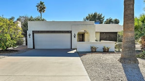A modern house with a garage, a small patio area, and a palm tree.