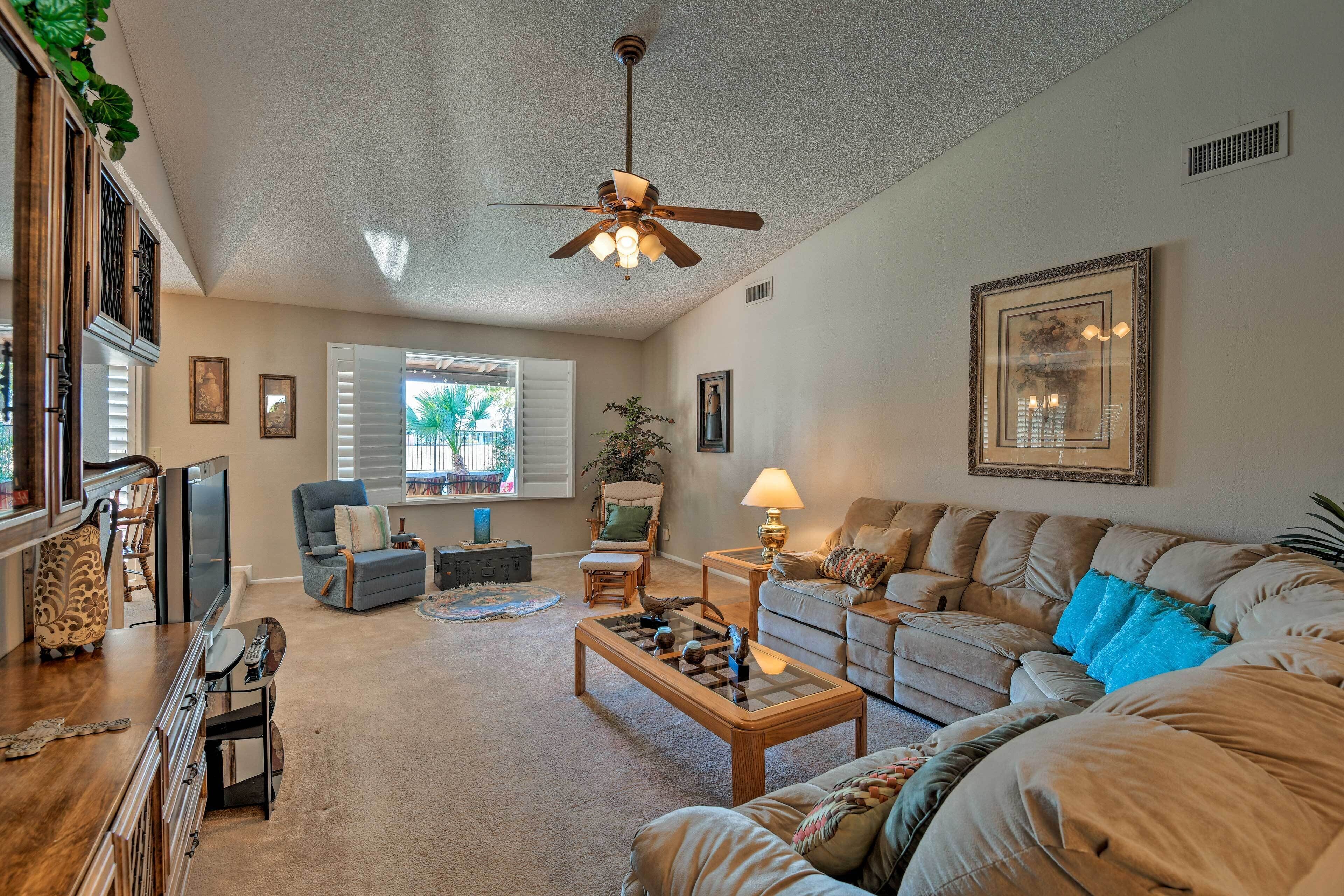 A spacious living room with a ceiling fan, a sofa set, a coffee table, and a television.